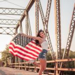 Woman holding an American flag outdoors on a bridge for 4th of July