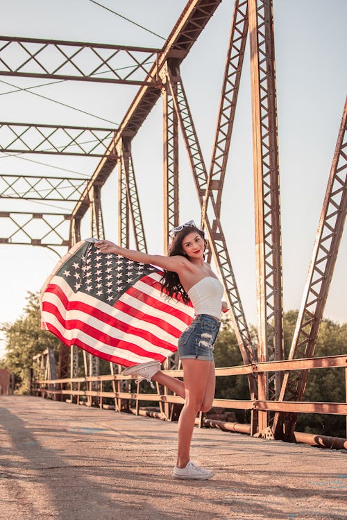 Woman holding an American flag outdoors on a bridge for 4th of July