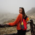 Woman in hiking outfit on a dramatic mountain trail wearing outdoor gear and a bright jacket