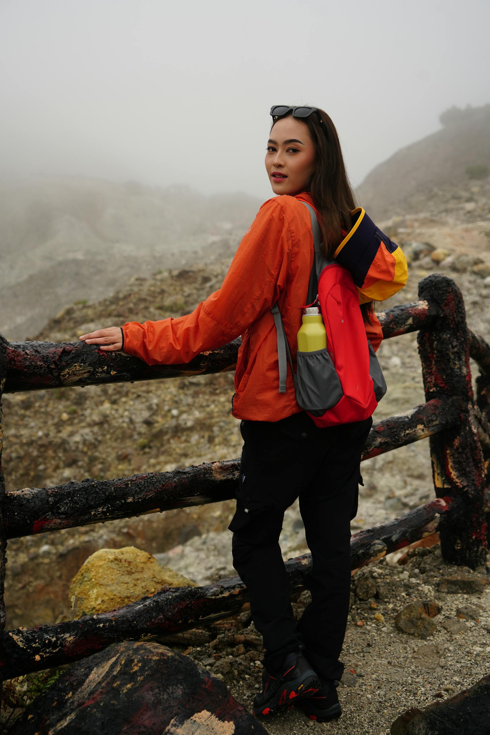 Woman in hiking outfit on a dramatic mountain trail wearing outdoor gear and a bright jacket