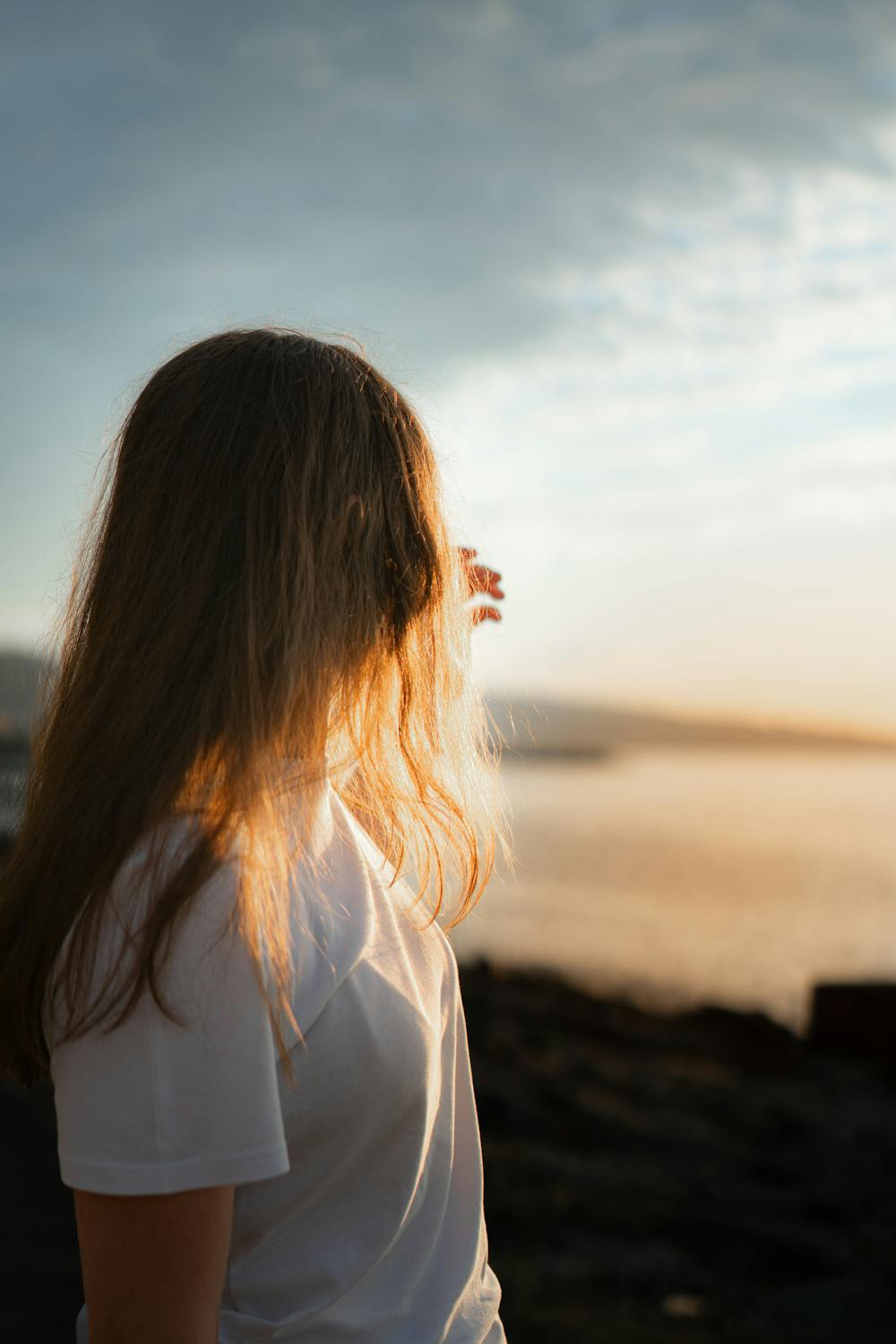 Woman posing at the beach during golden hour with warm sunlight behind her