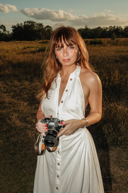 Woman holding a camera in a sunlit field during golden hour