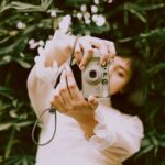 Woman holding a digital camera outdoors in a natural setting