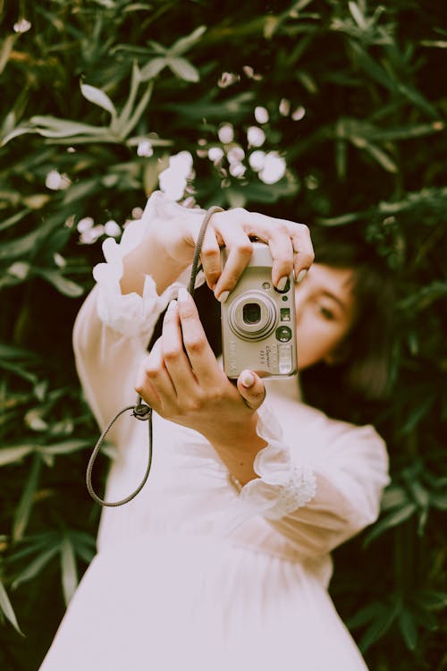 Woman holding a digital camera outdoors in a natural setting