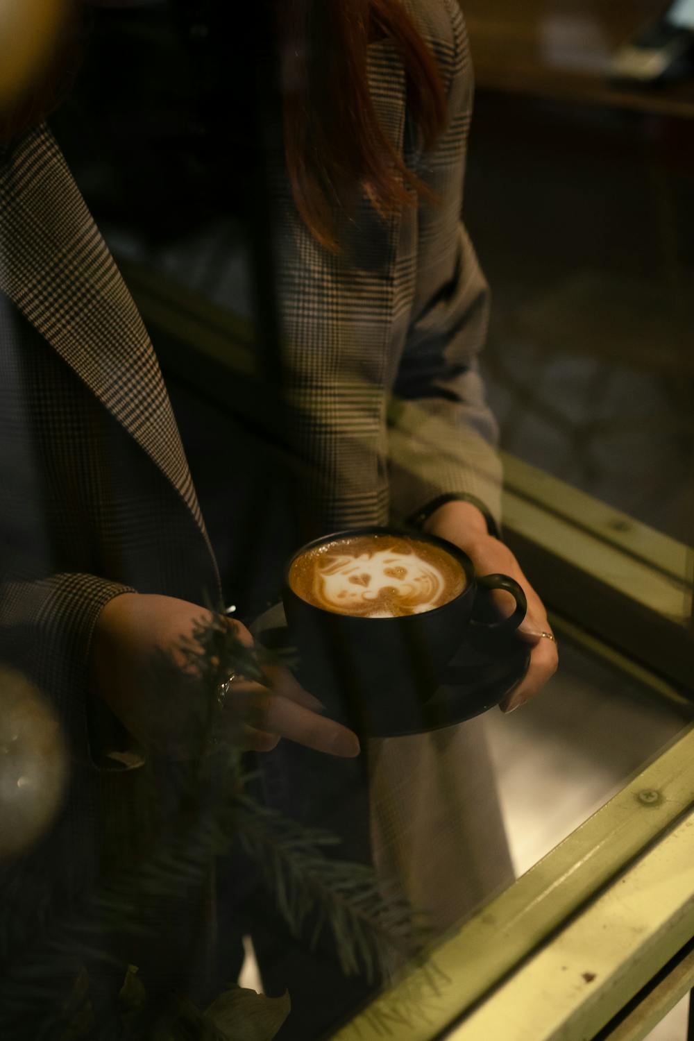 Woman sitting in a cafe with an aesthetic latte art cup on the table