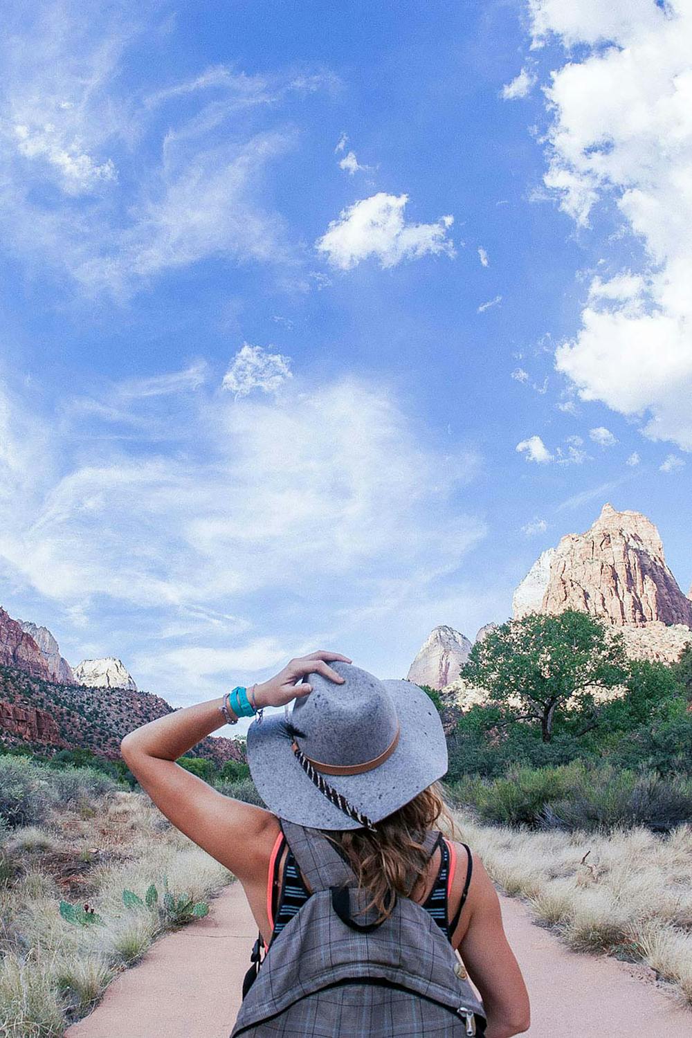 Woman hiking on a scenic mountain trail with a wide valley view behind her