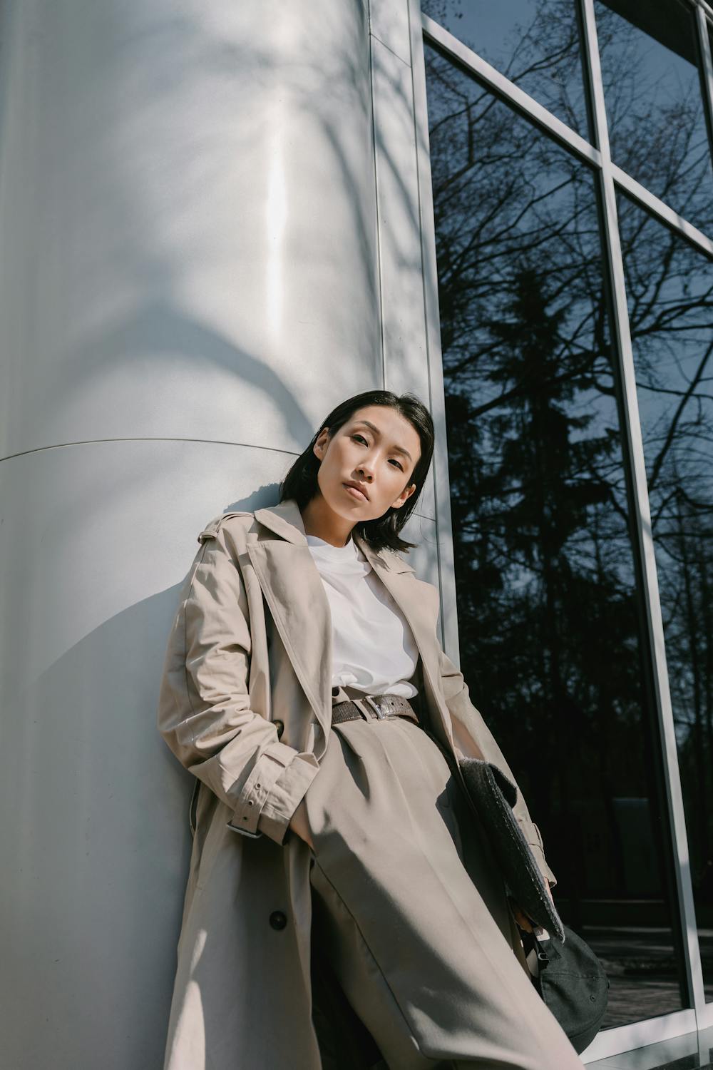 Woman in a minimalist city outfit wearing a beige trench coat on a city street