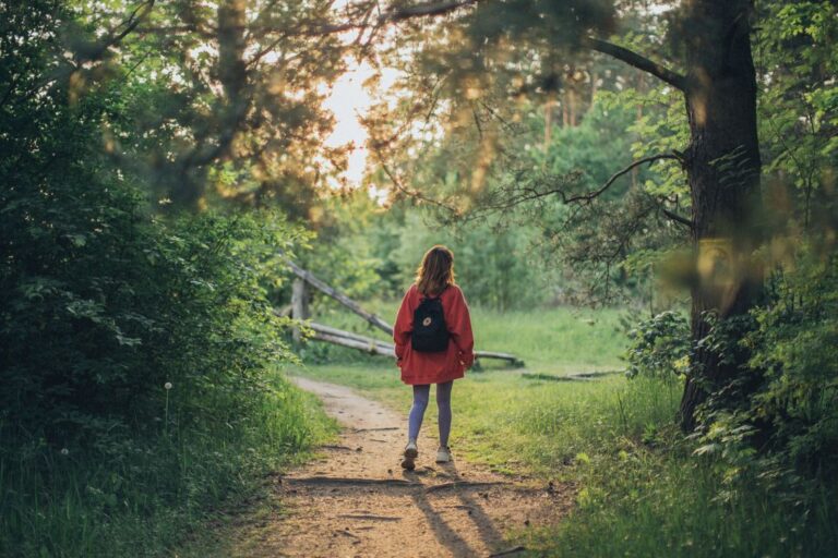Woman with a hiking backpack walking through a forest trail