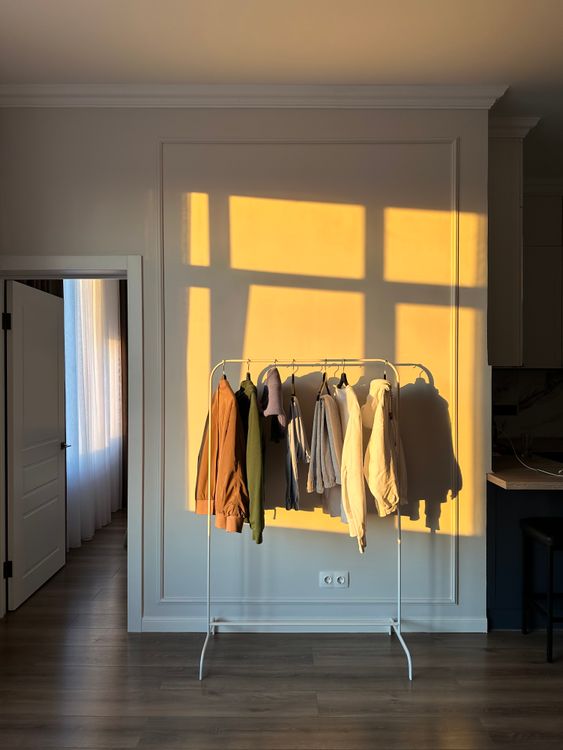 Minimalist clothing rack with neutral garments in warm morning sunlight