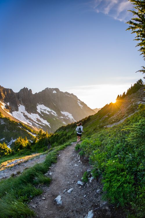 Woman hiking on a mountain trail at sunset with scenic views